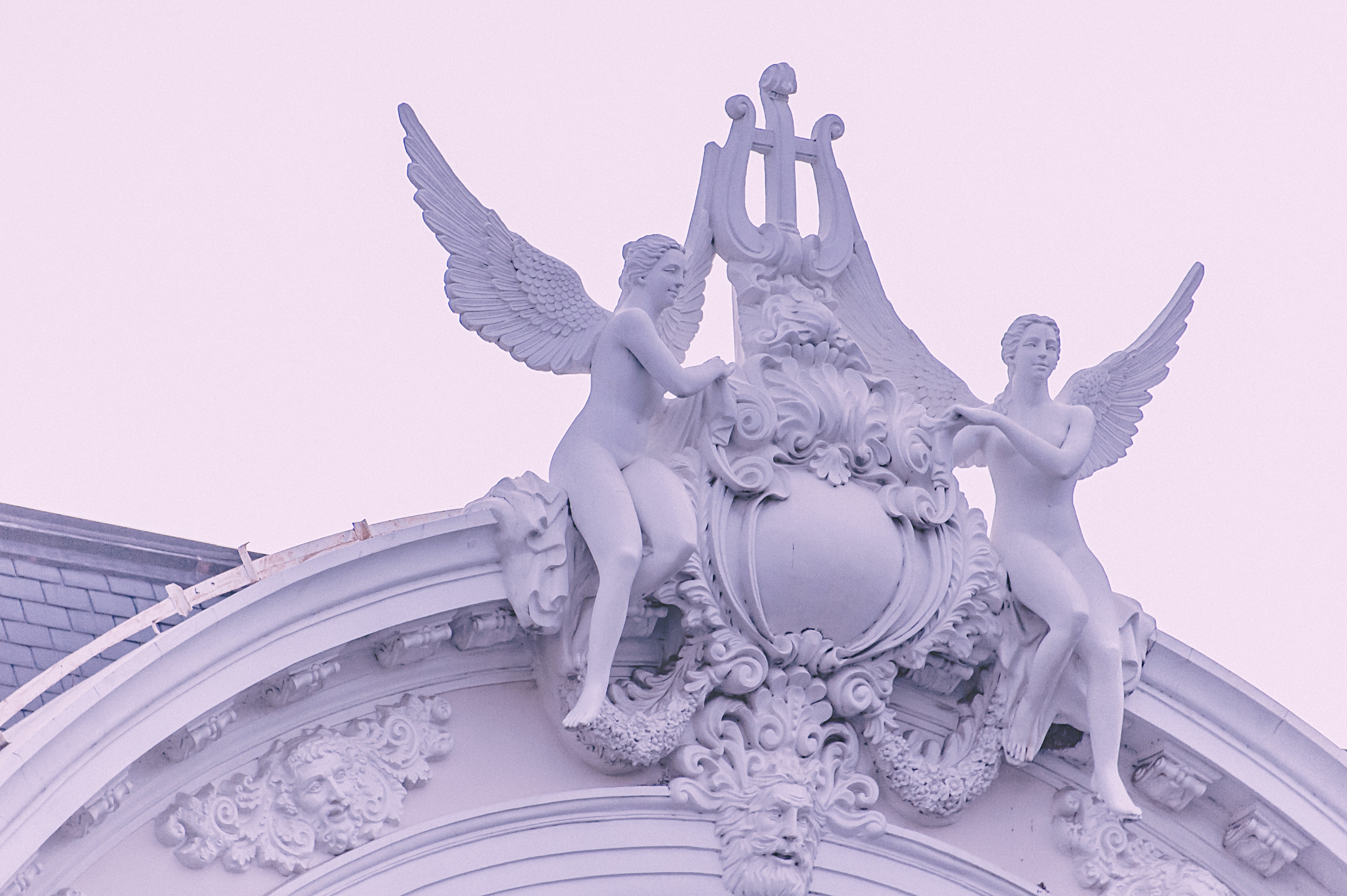 Two Sculptures Of Female Angels Above A Building