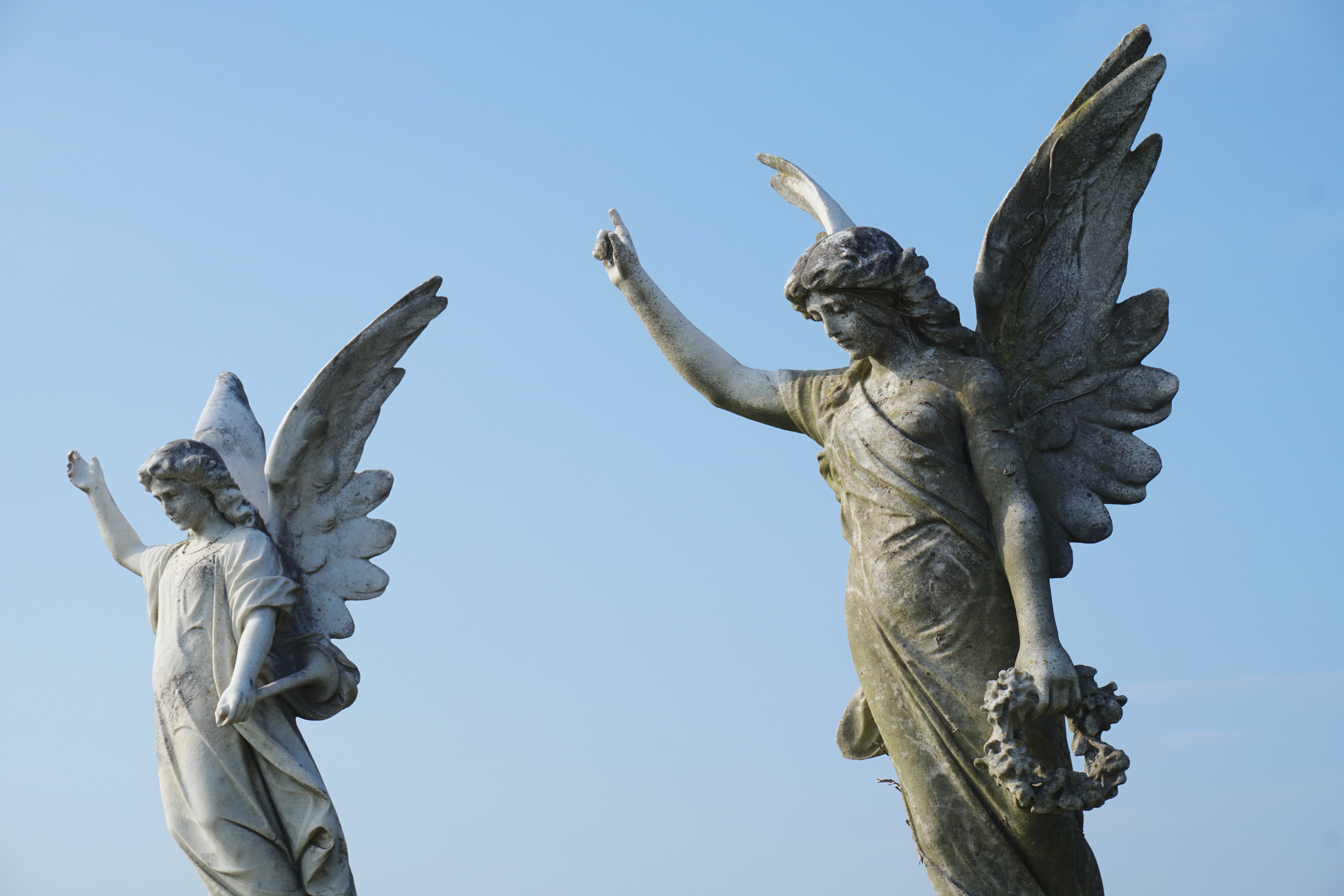 Two Angels Sculptures With A Light Blue Background