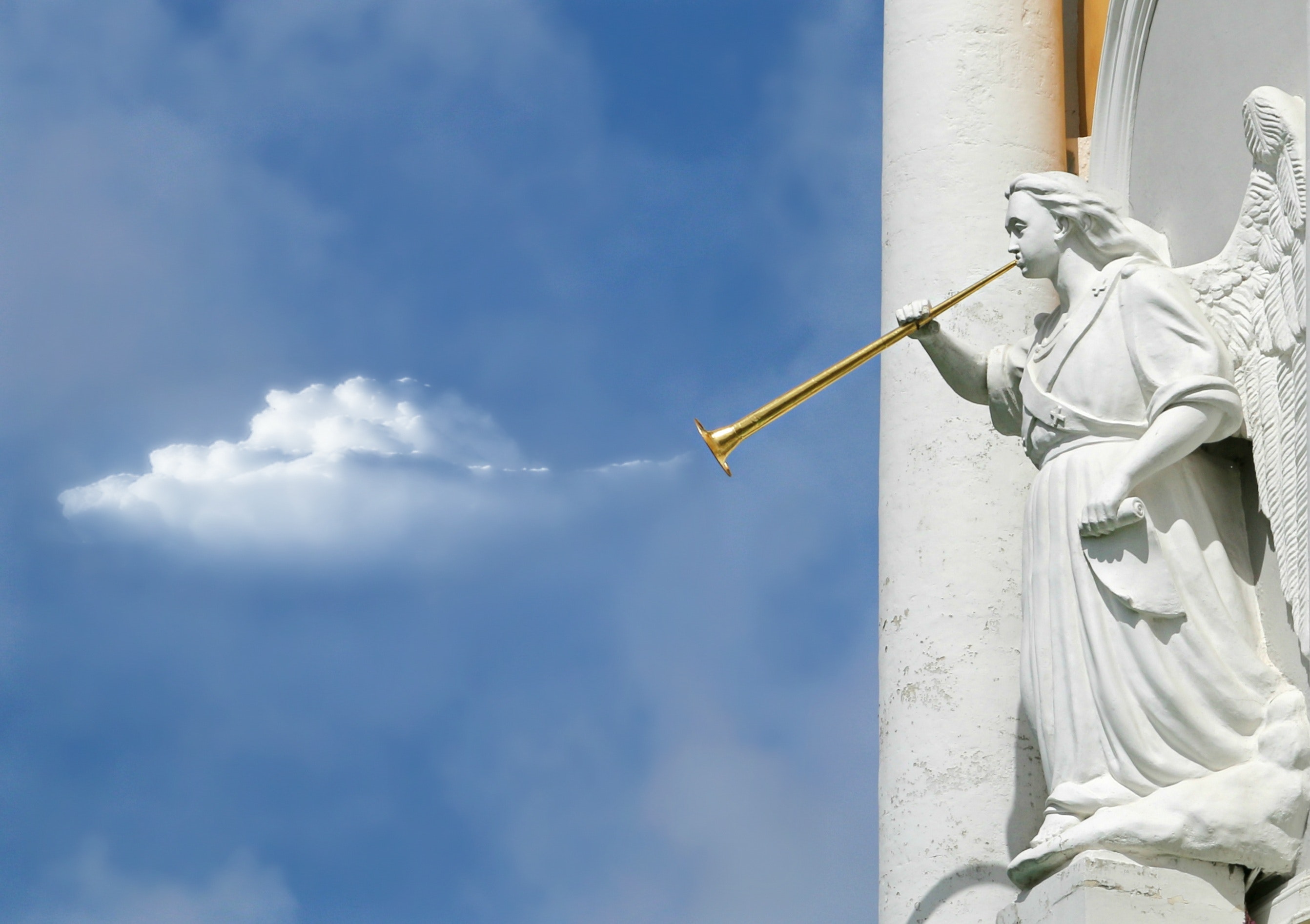 Angel sculpture holding a trumpet with bright blue sky