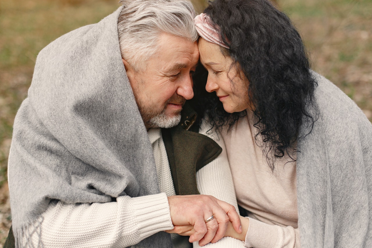 Old Man and Woman looking at Each Other with a thick blanket on their backs