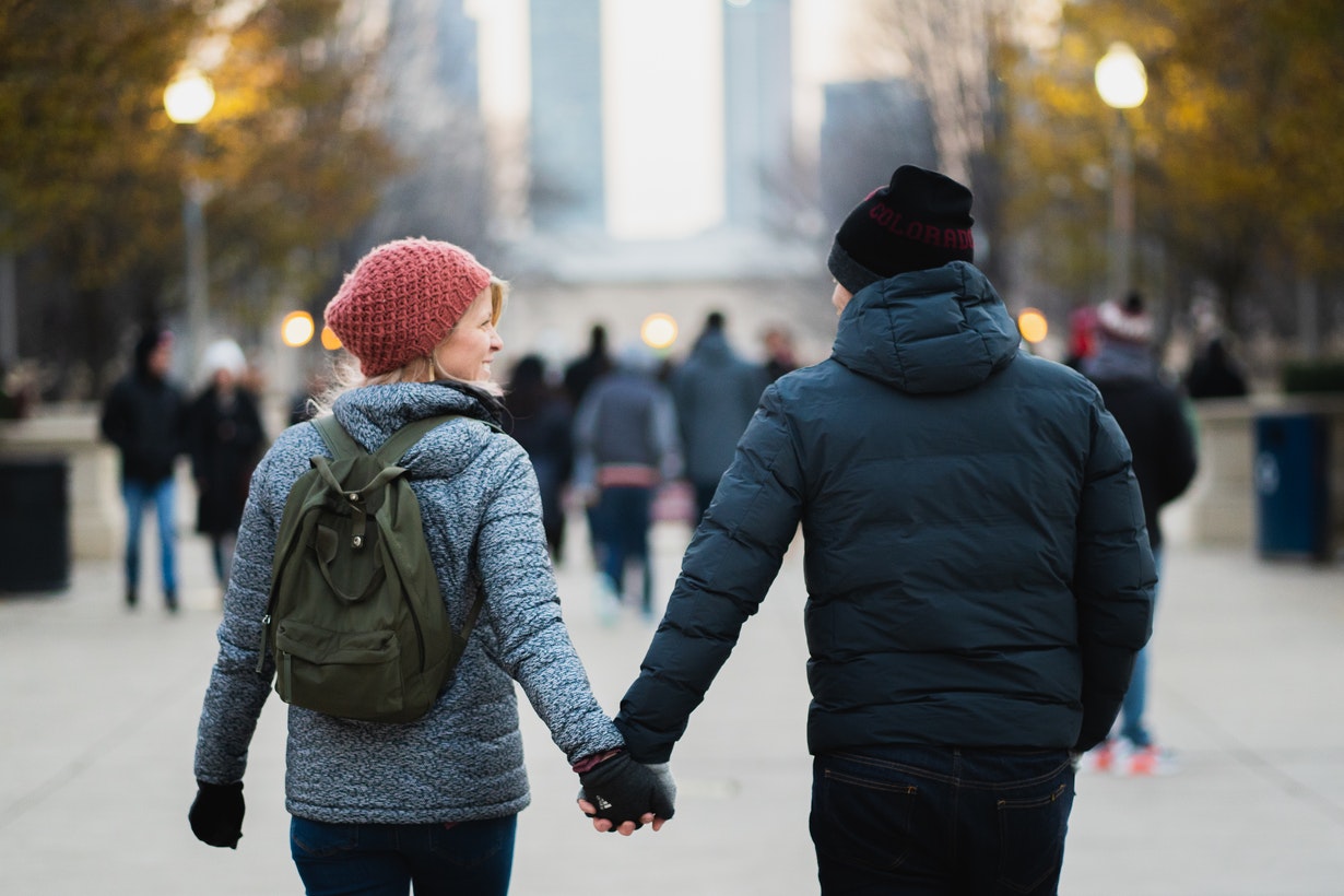 Man and Woman Holding Hands While Walking at Busy Street