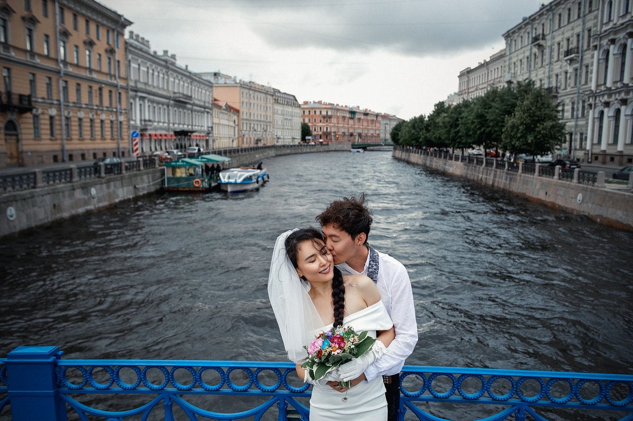 Couple Standing on Bridge wth Blue and White Boat on River