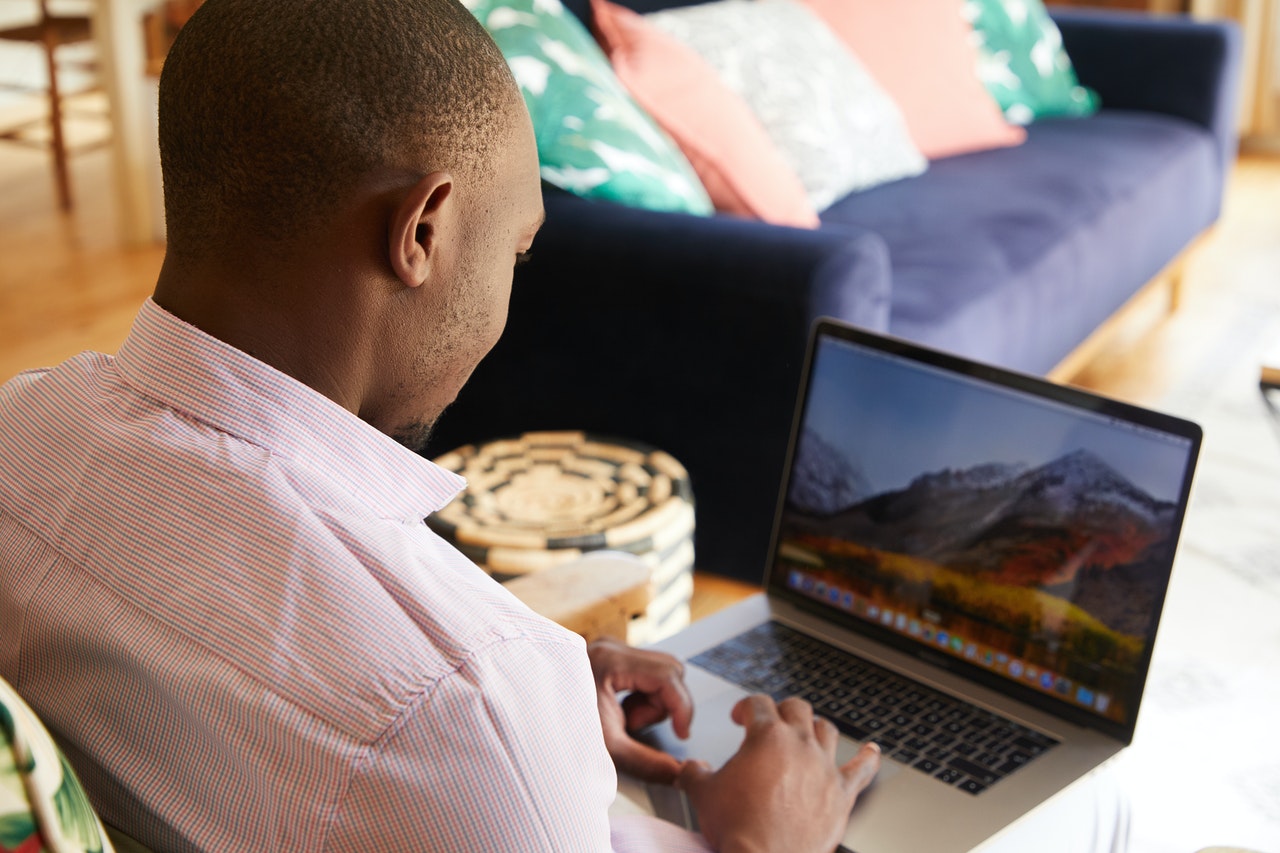 Black man using on laptop in cozy room
