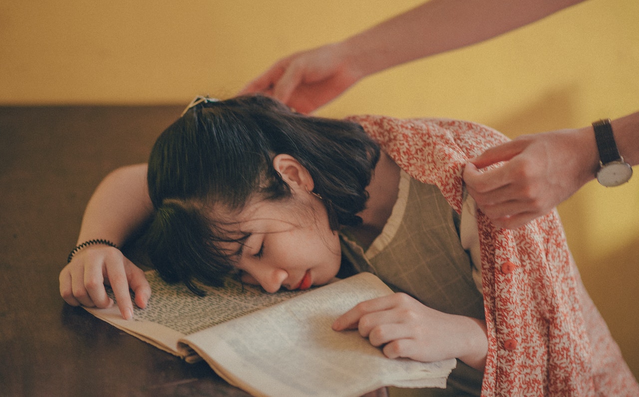 Women sleeping on table with an open book on her face