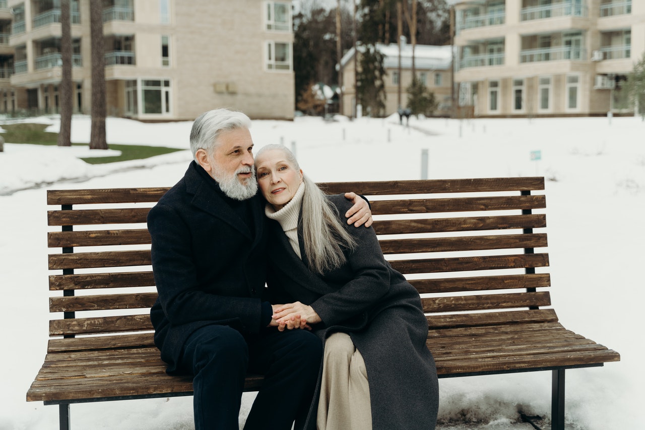 An Elderly Couple Embracing while Sitting on a Wooden Bench.jpg