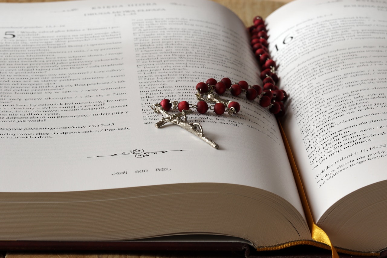 Red Rosary on Top of An Open Bible
