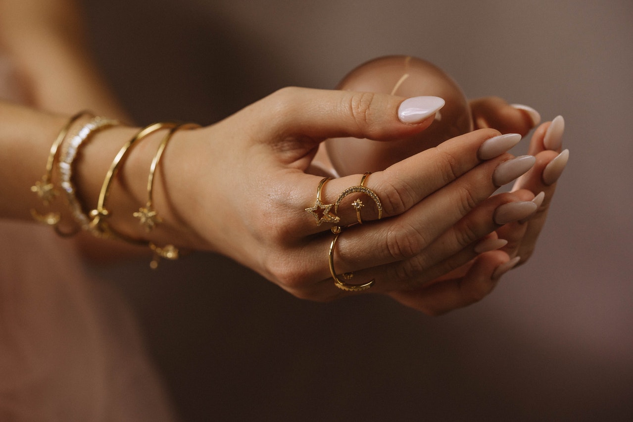 Woman Wearing Gold Rings and Gold Bracelets holding a small brown ball in her hands