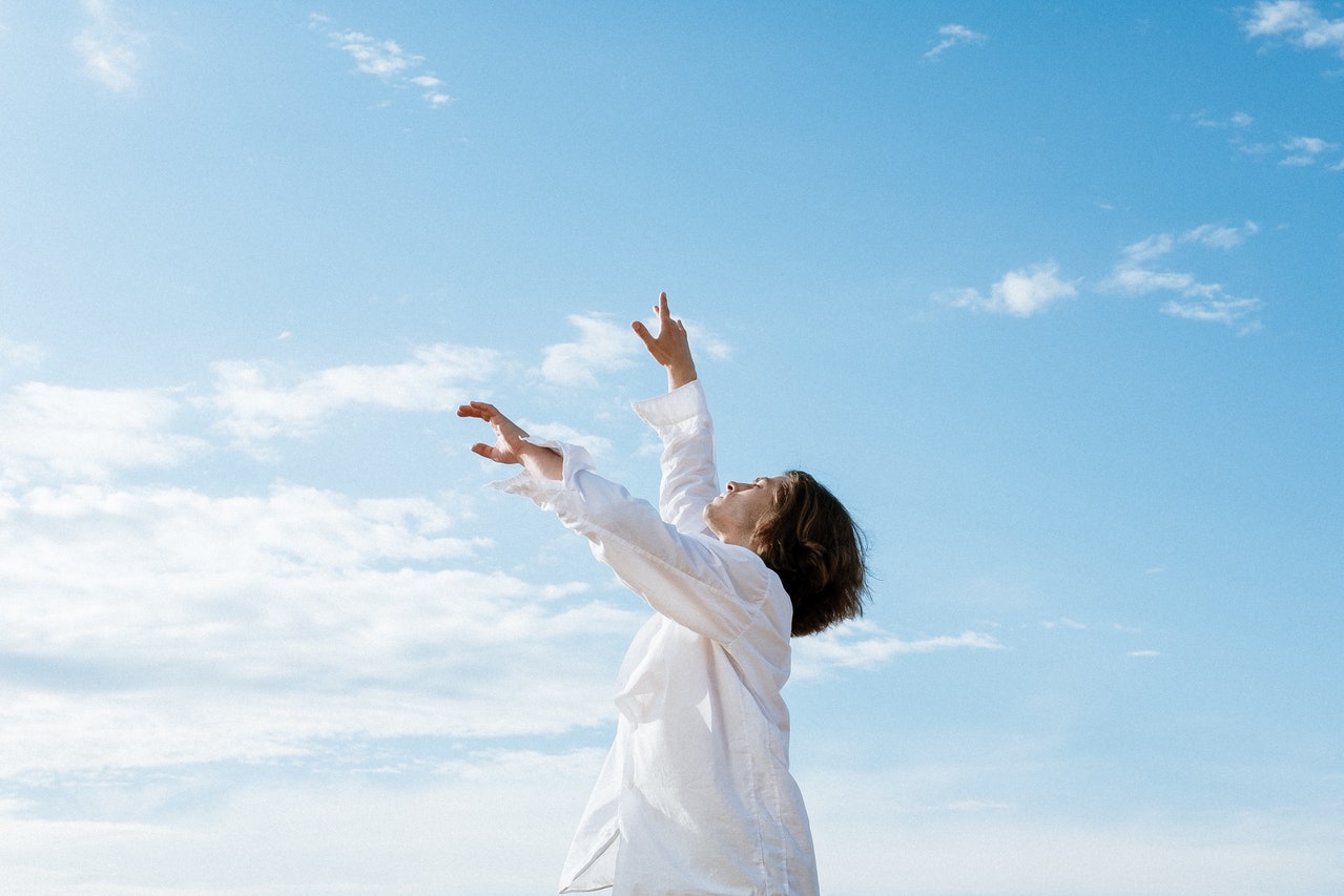 A Woman in White Long Sleeve Shirt Raising Her Hands Up In The Air