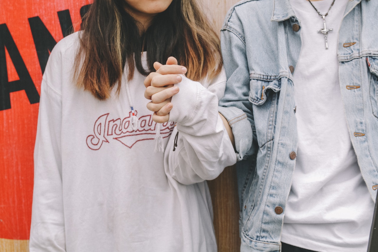 A Couple wearing sweater and jean jacket Holding Hands