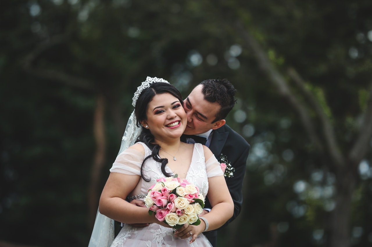 Man in Black Suit Hugging Woman in White Floral Wedding Dress