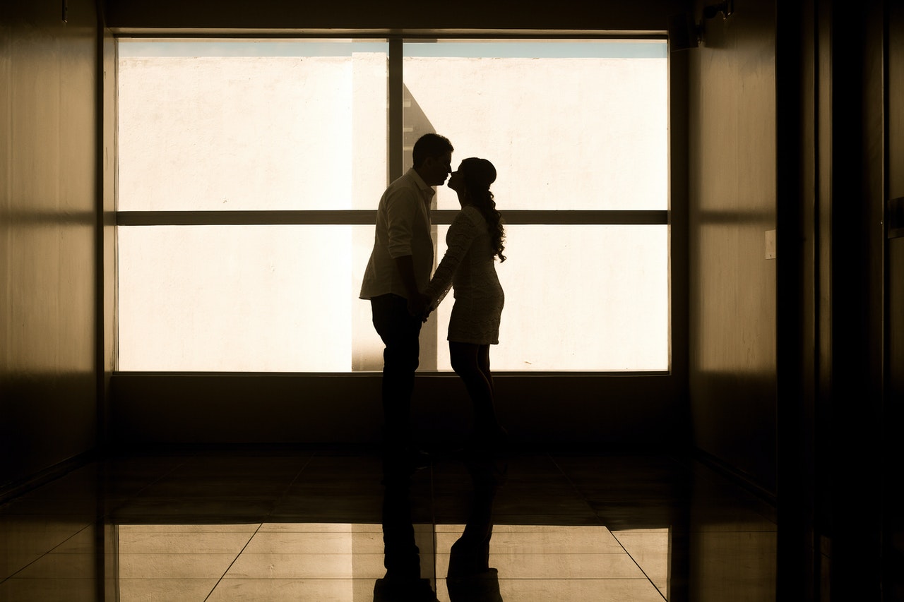A Man and a Woman Holding Hands Near Glass Window