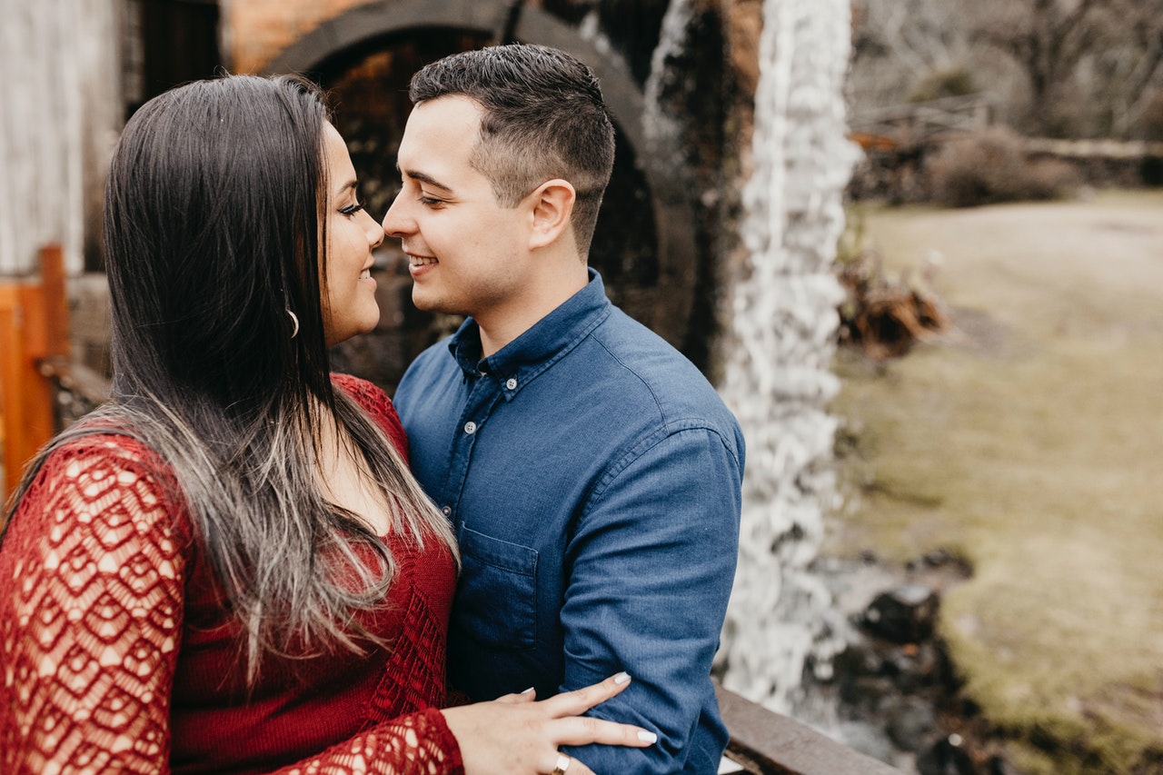 Content multiracial couple embracing near waterfall during trip