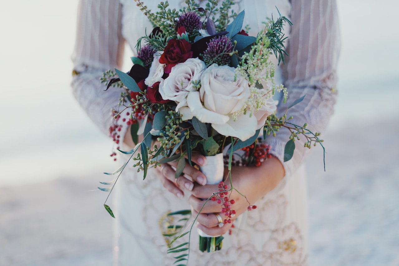 Woman Holding Red and White Rose Bouquet while standing on the beach