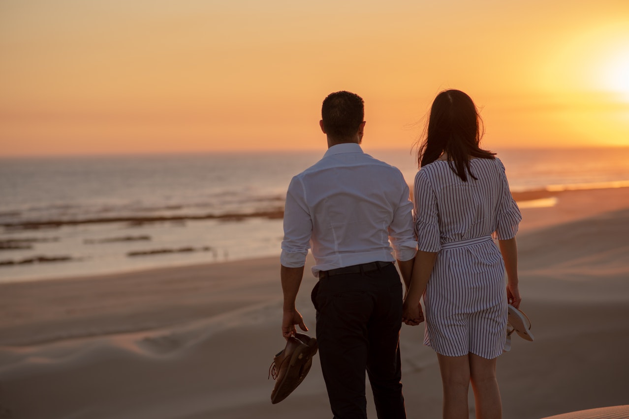 Couple Standing on Beach during Sunset while holding hands