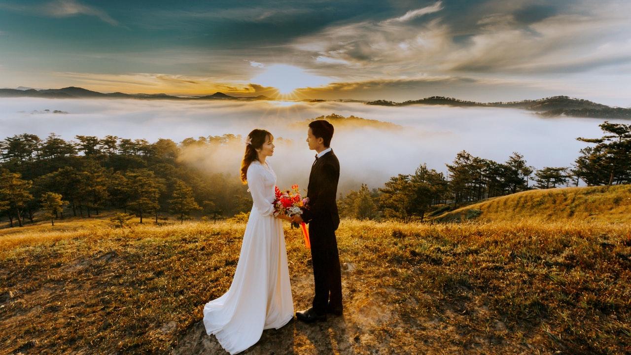 Couple Standing On top of a mountain While Looking At Each Other