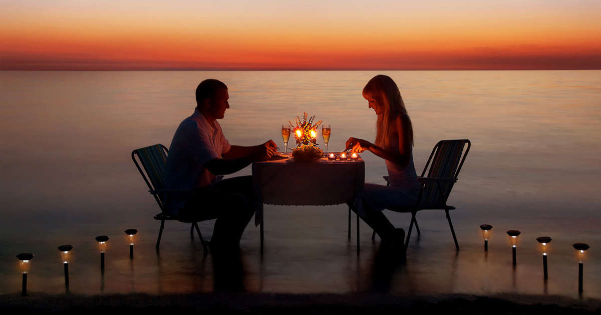 A couple having dinner together by the lake and sunset