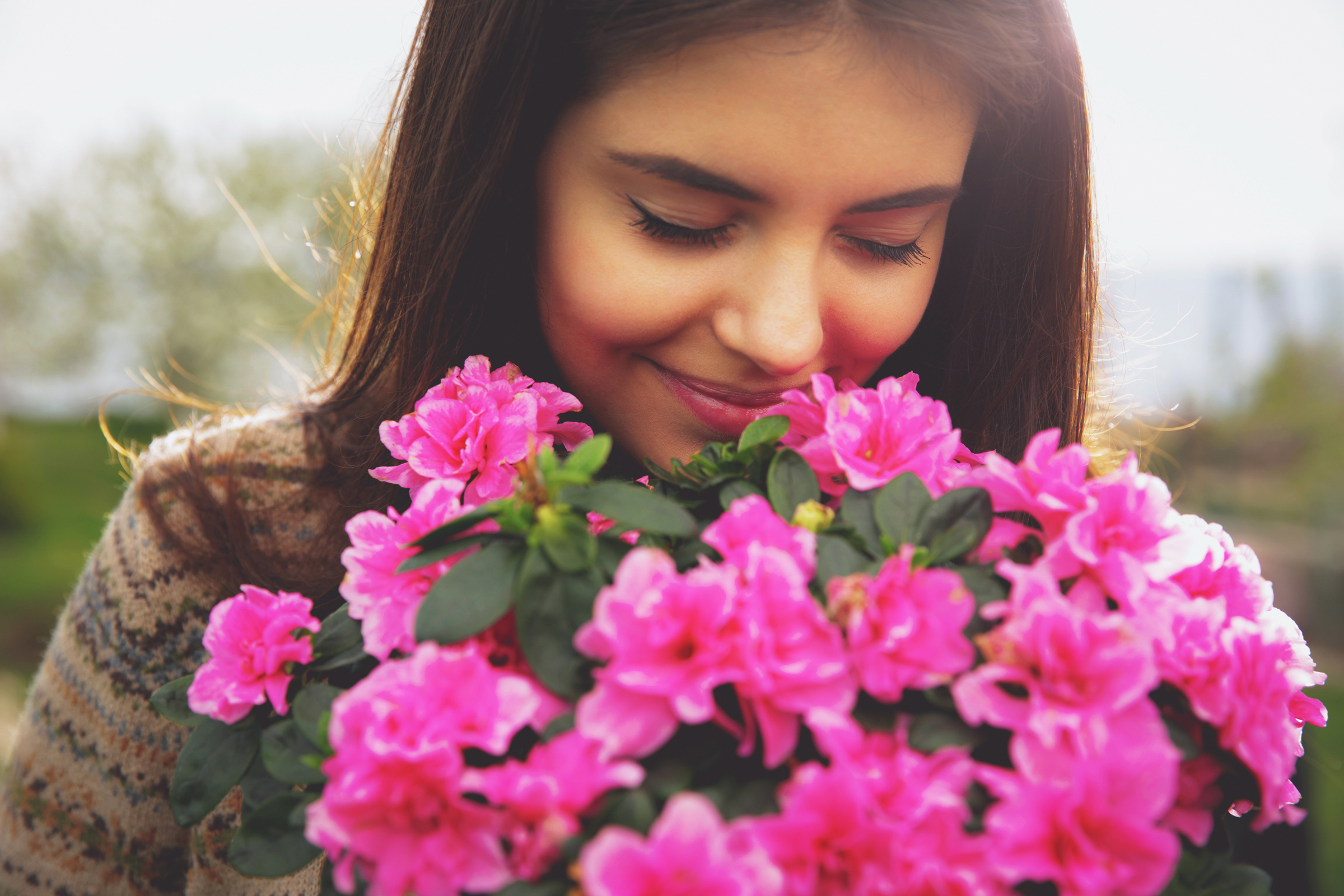 A girl holding a bouquet of flowers and smelling fresh fragnance while smiling