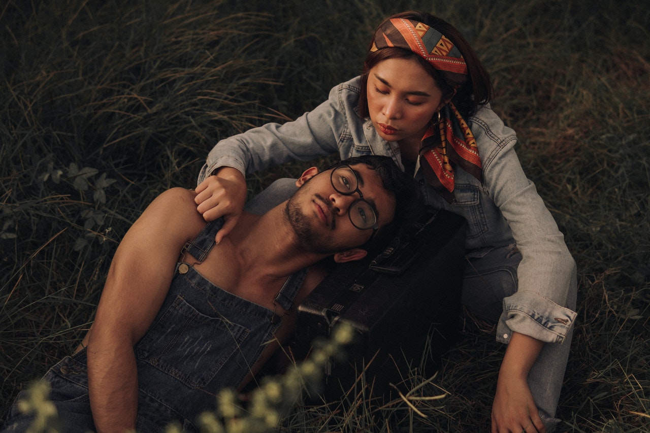 A couple lying and sitting on a grassy field