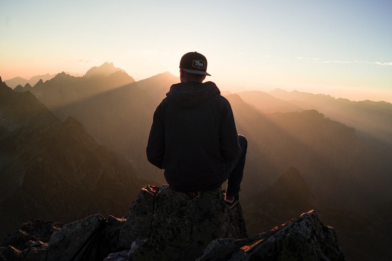 Man wearing a cap backwards Sitting on the Mountain Edge