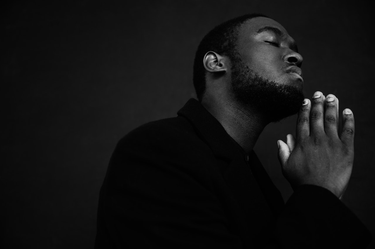 Black man praying with eyes closed
