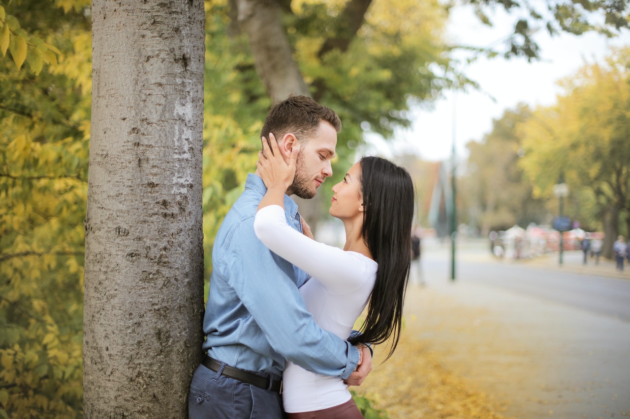 A Couple Hugging And Looking at Each Other While Standing Next to a Tree