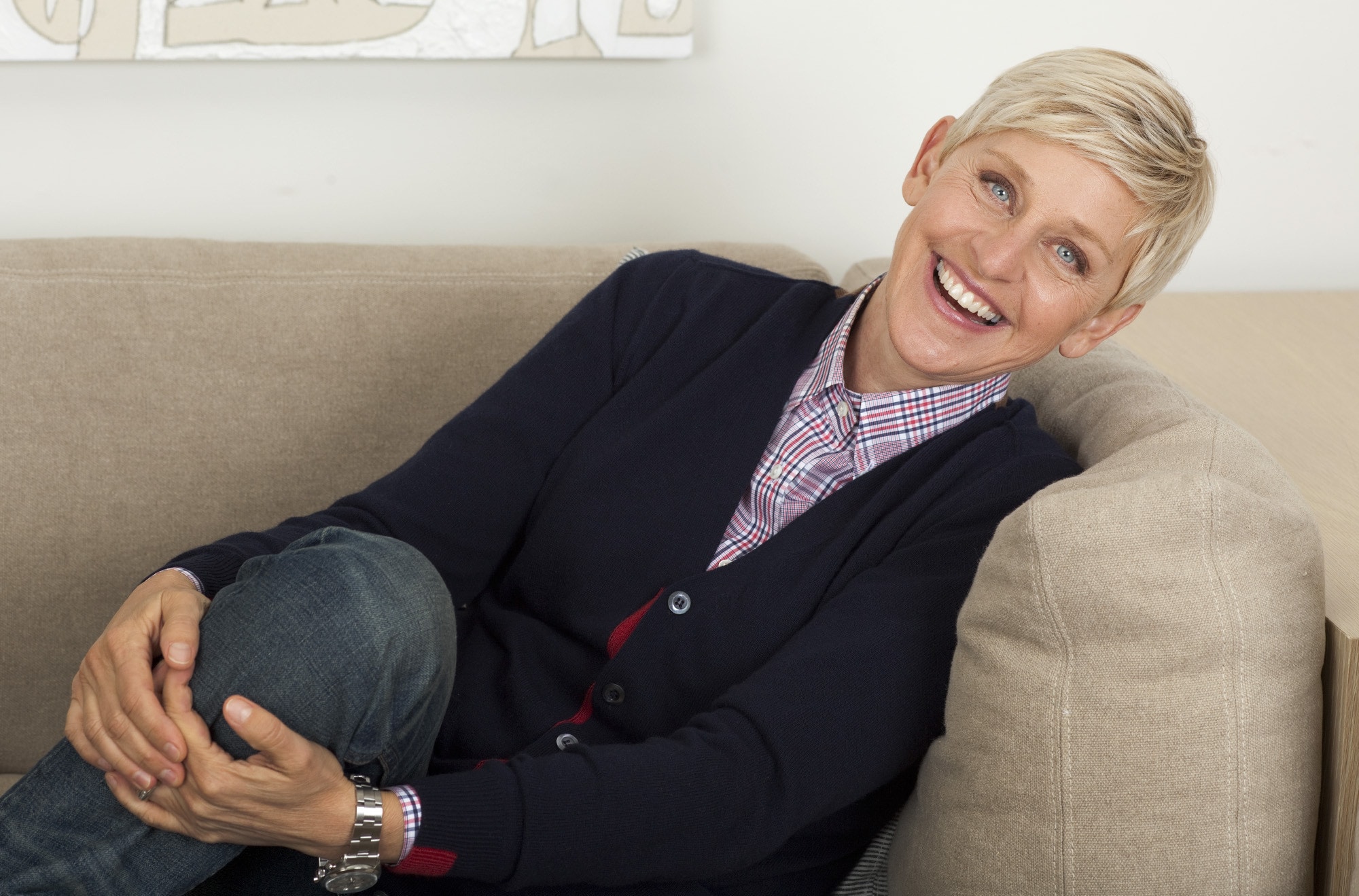 Ellen DeGeneres smiling while sitting on the couch