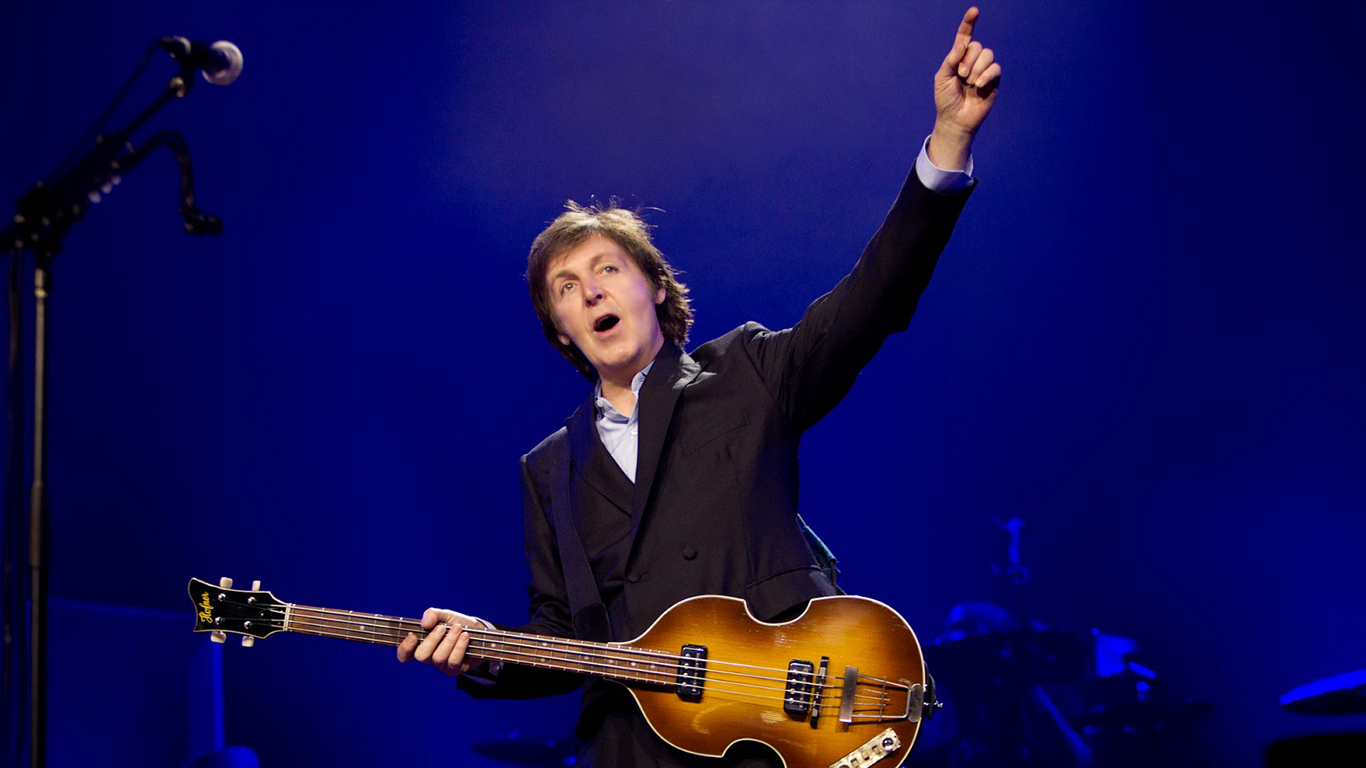 Paul McCartney singing while holding a guitar