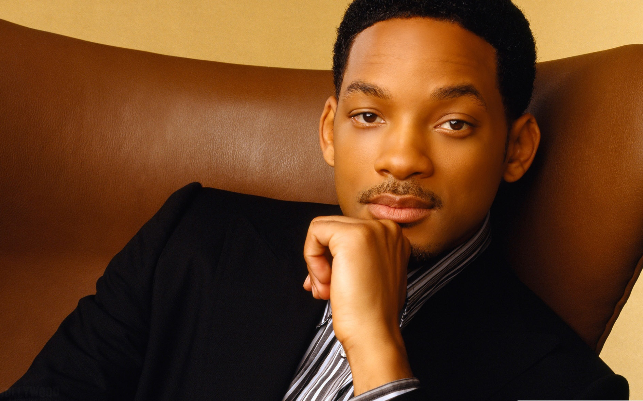 Will Smith sitting on a couch with his hand on his chin