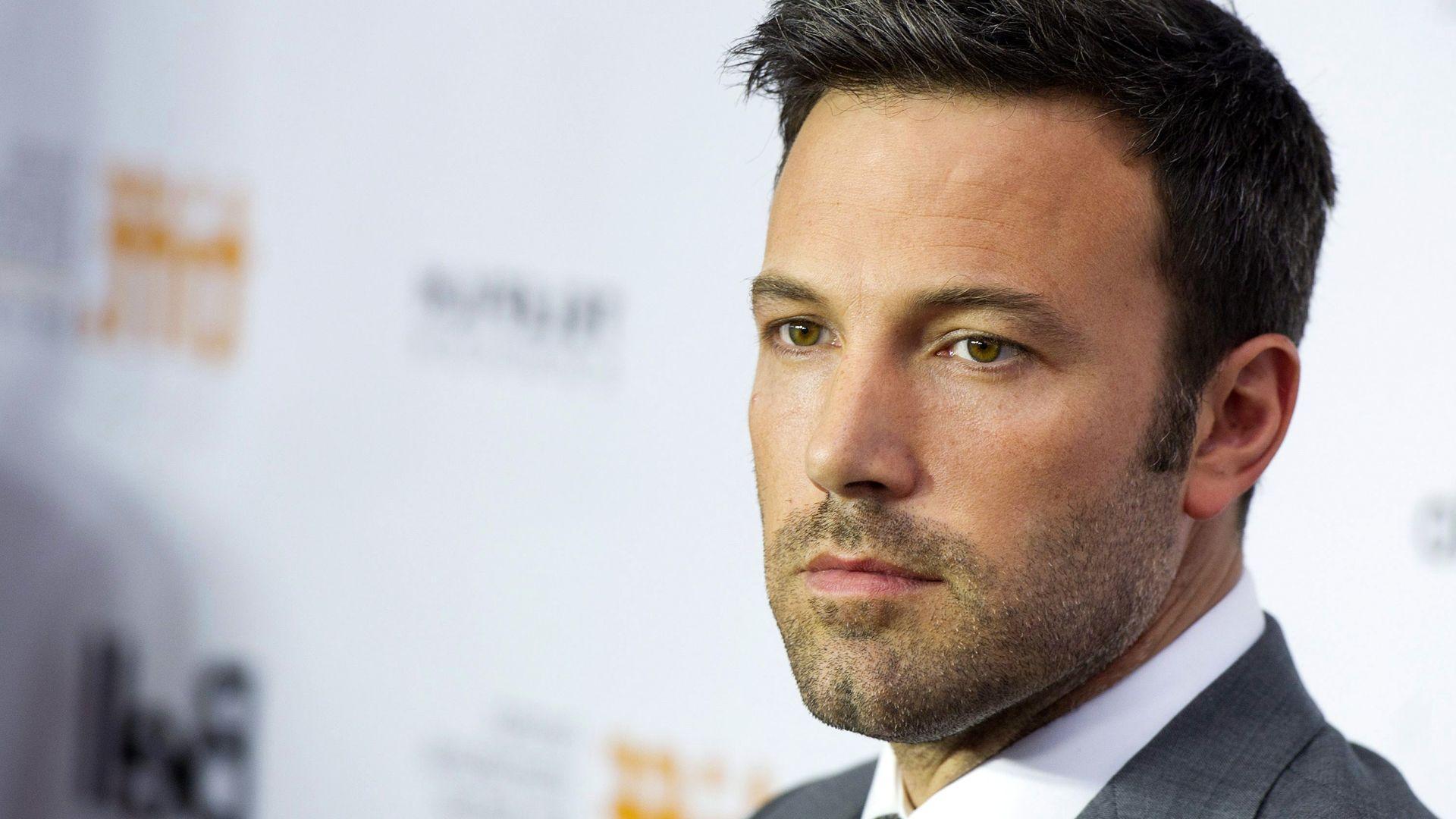 Handsome Ben Affleck with shaved beared and wearing a gray suit