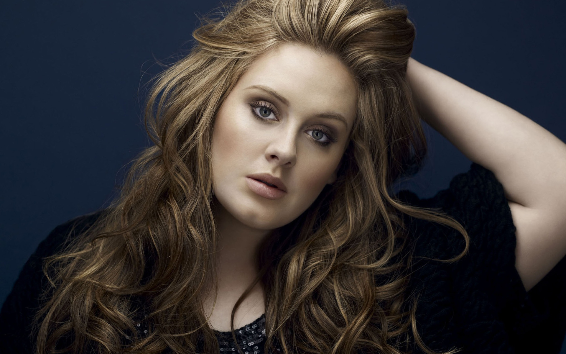 Adele with curly blonde hair with her hand on her head