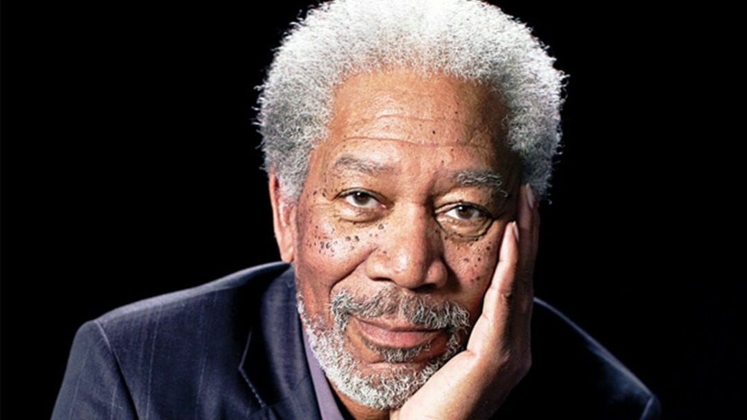 Morgan Freeman smiling with his right hand on his face