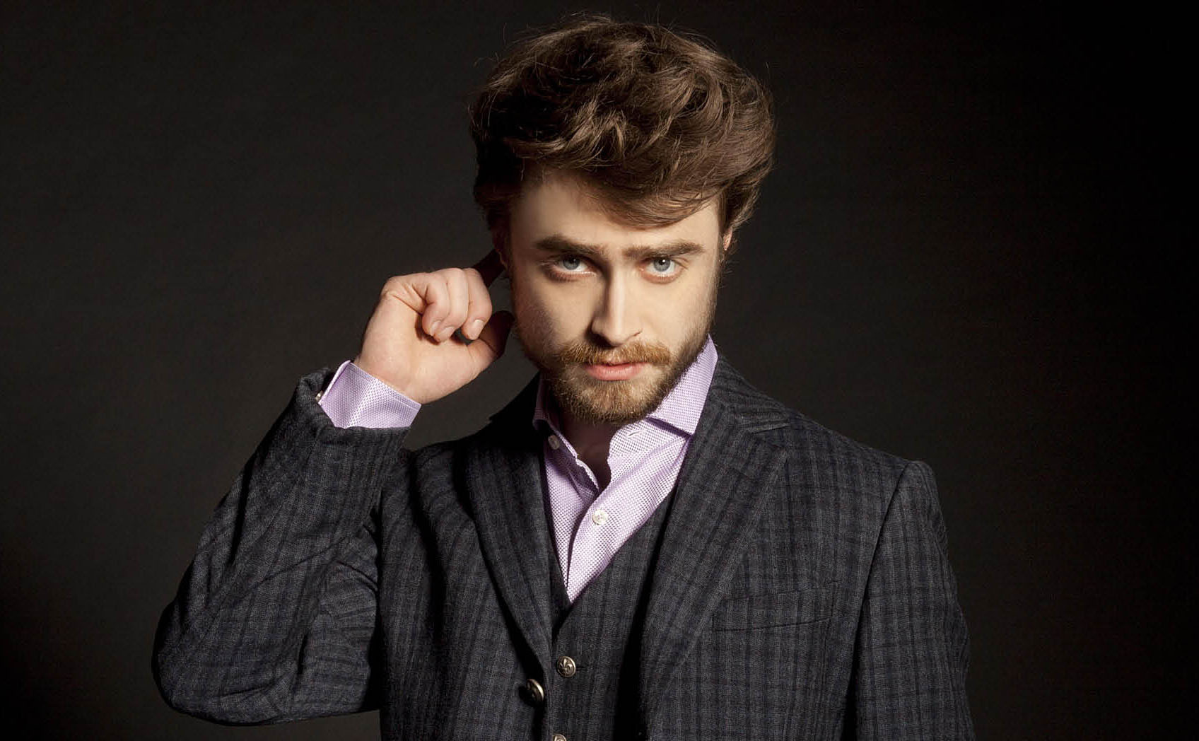 Daniel Radcliffe with beard and wearing a gray suit 