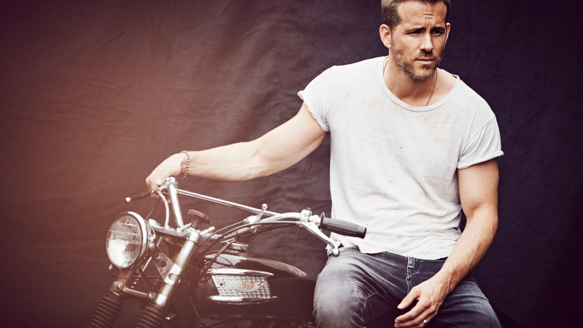 Ryan Reynolds wearing white shirt while sitting on a motorcycle