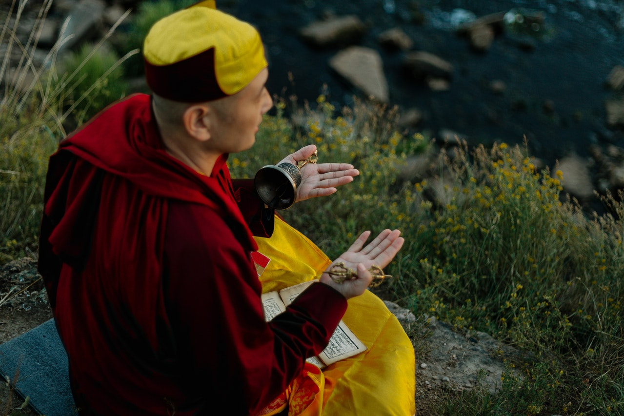 Man in Red Hoodie and Yellow Knit Cap Praying Near A Cliff