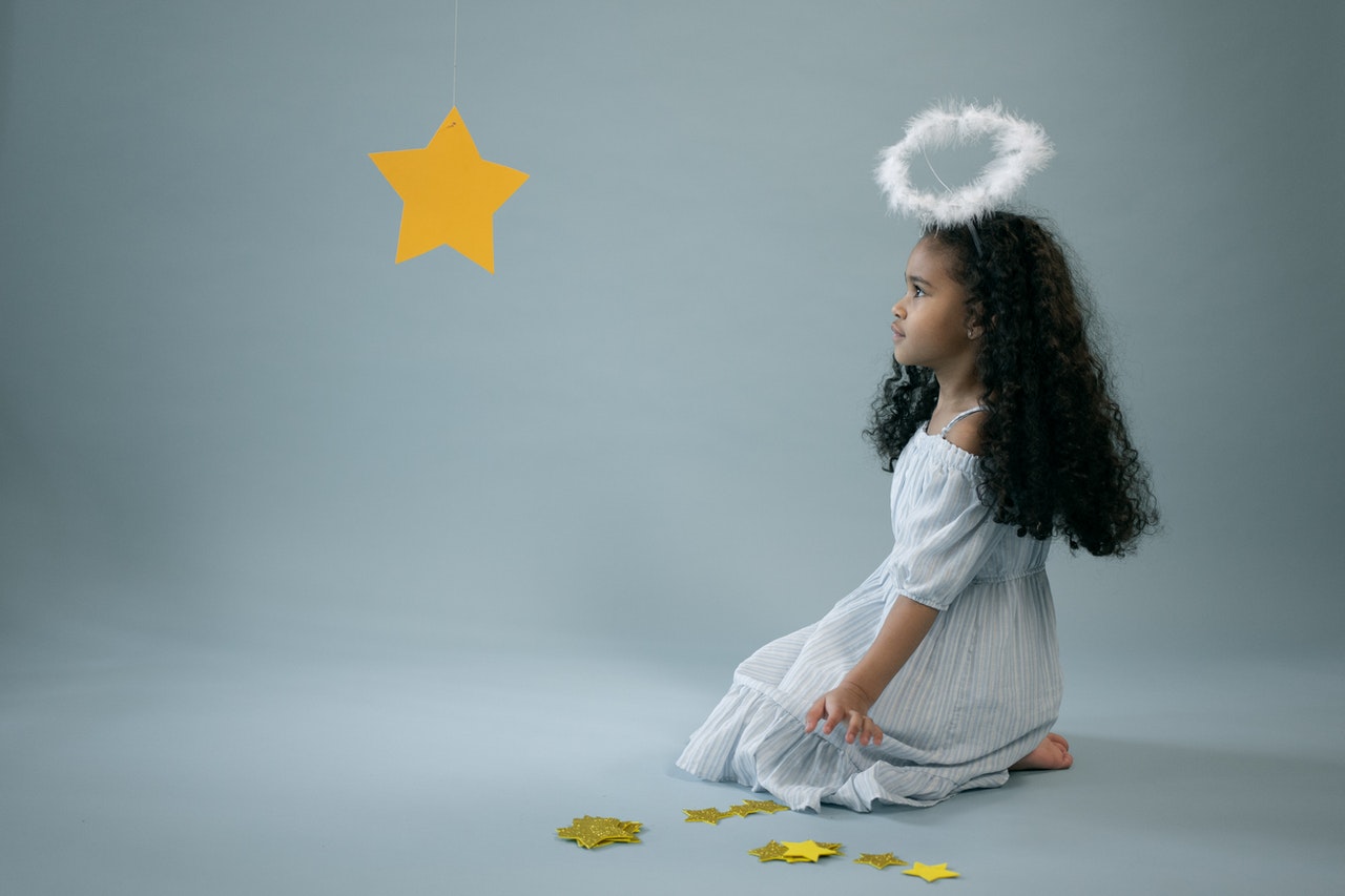 Adorable girl in angel costume near hanging star