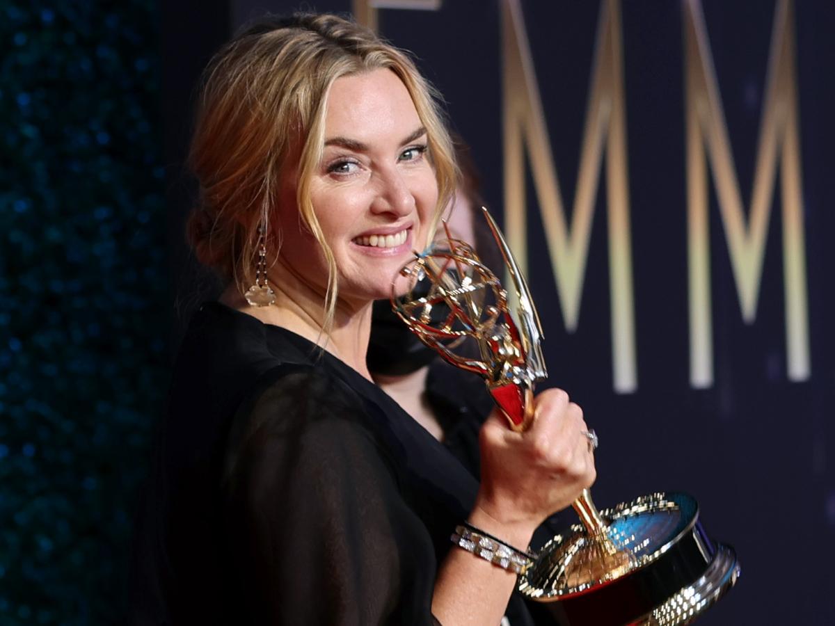 Kate winslet smiling while holding a trophy