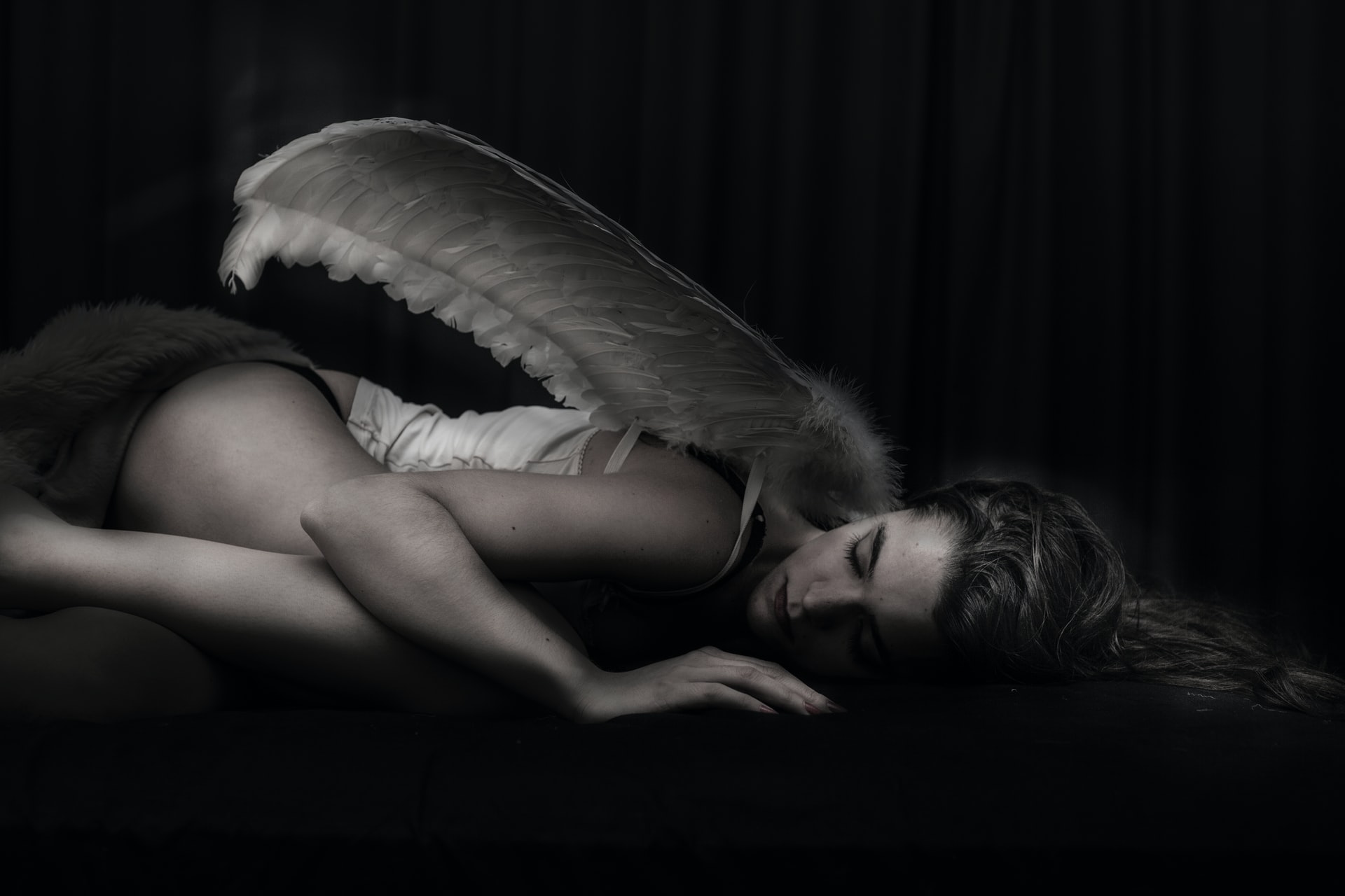 Woman With Wings Lying In A Dark Room