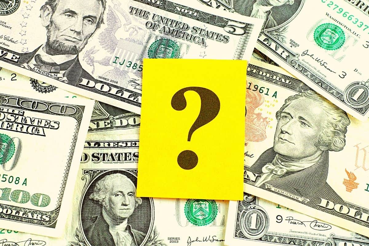 Different dollar bills with a yellow paper at the center with a question mark