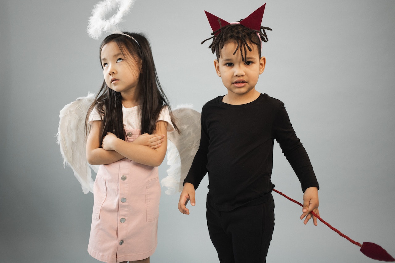 Cute multiracial kids in angel and devil costumes