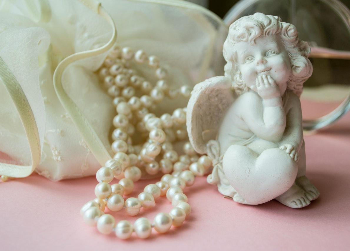 Angel Figurine Beside a Pearl Necklace