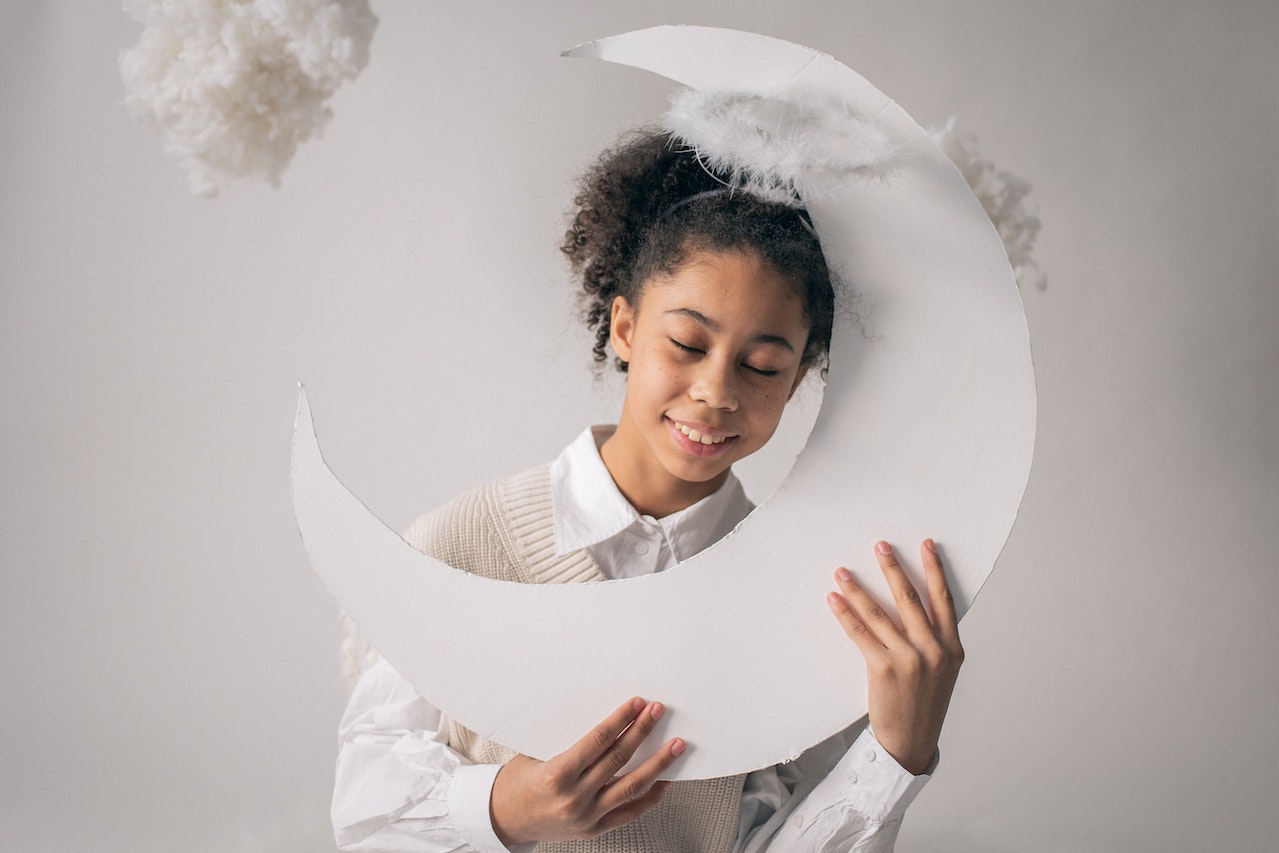 Smiling kid with eyes closed holding a handmade moon