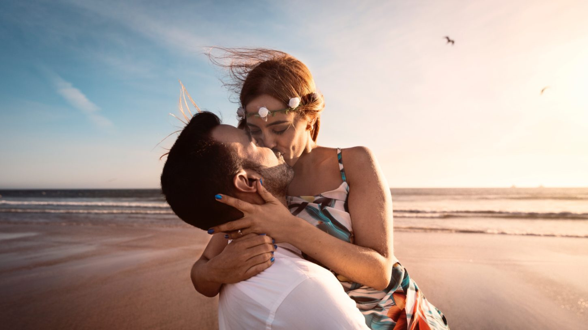 A couple kissing each other while on the beach