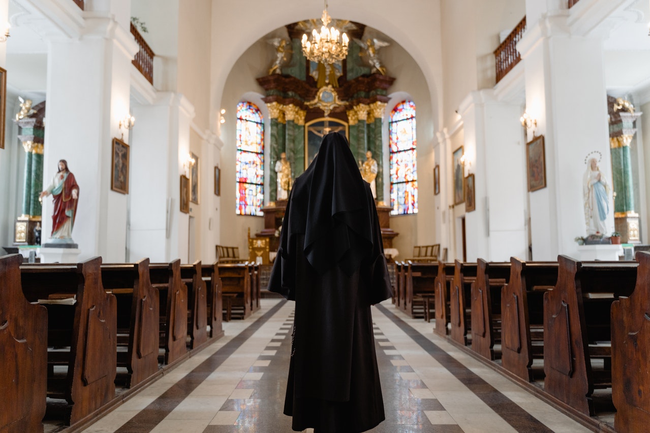 A Nun At The Aisle Of A Church
