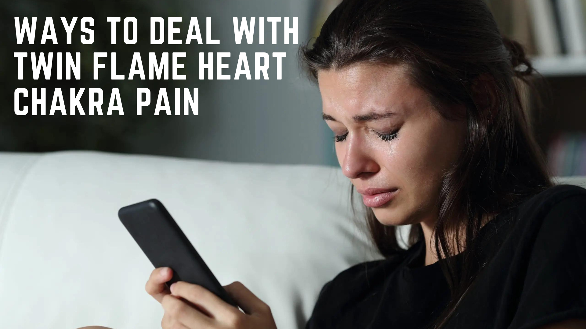 A crying woman sitting on the couch while holding a phone
