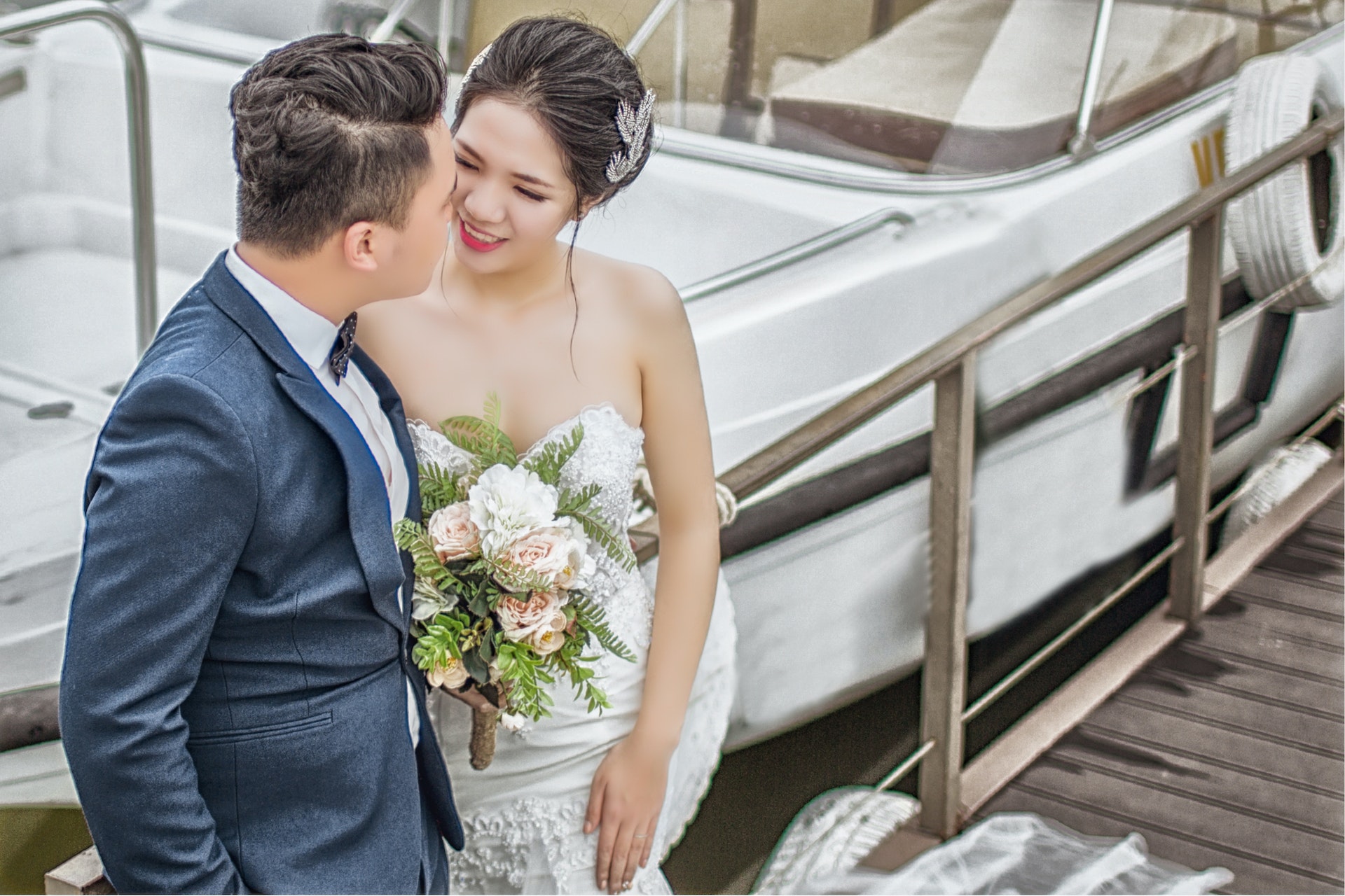 Newly Wed Couple Standing on Brown Wooden Dock Near Boat