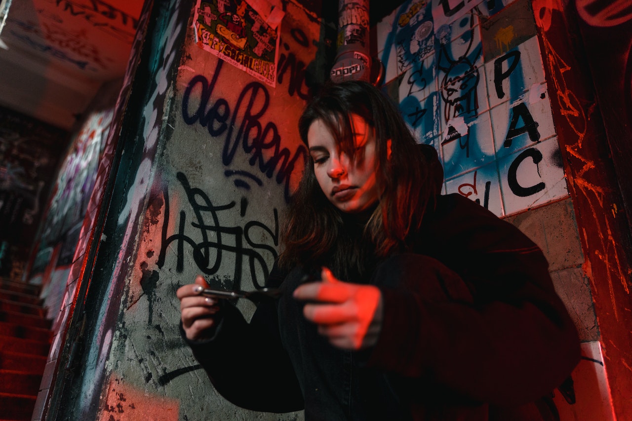 A woman standing in front of a wall full of graffiti while holding something