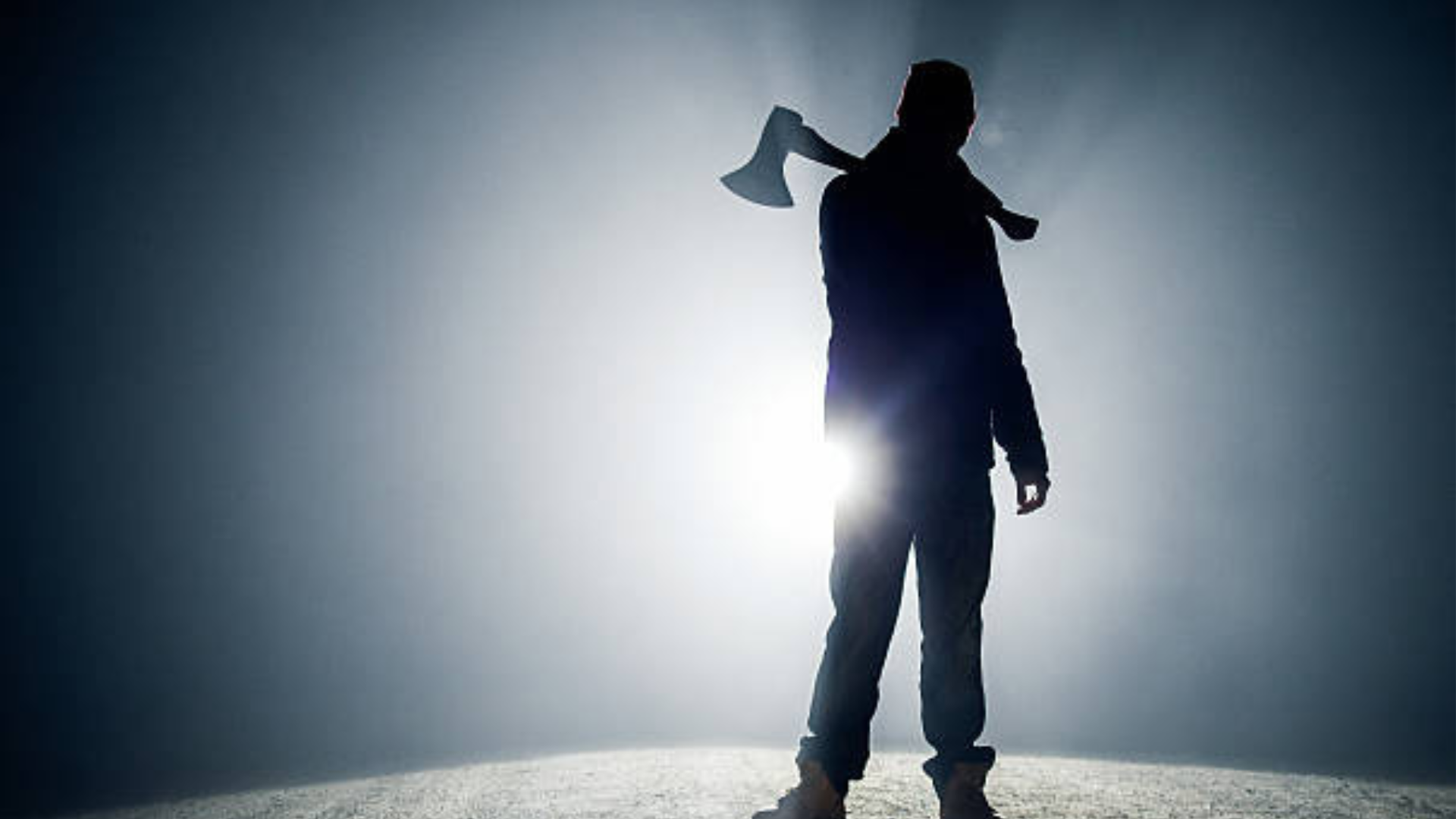 A man holding an axe and standing in the dark