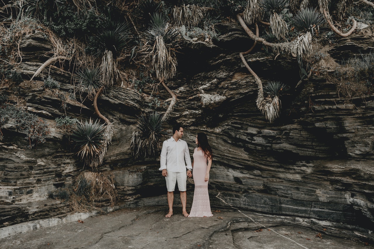 Loving couple holding hands while standing against rocky formation