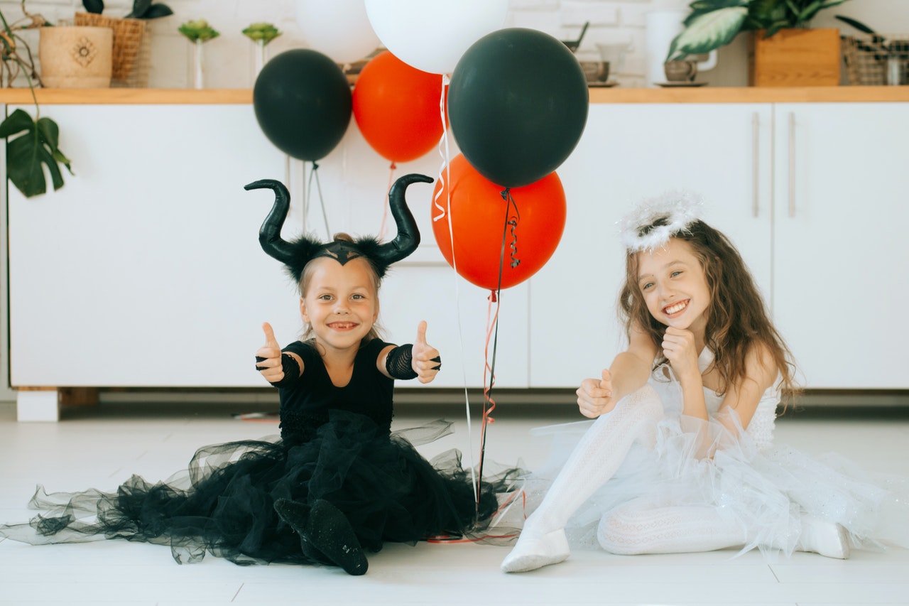 Duas garotas bonitas na fantasia de Halloween sentadas no chão