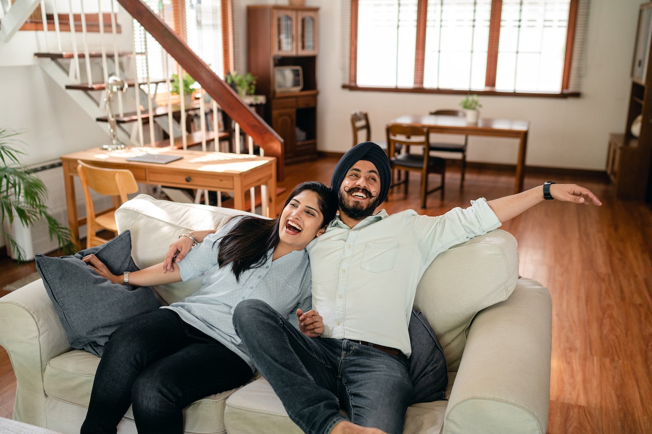 Delighted couple having fun on sofa in cozy apartment